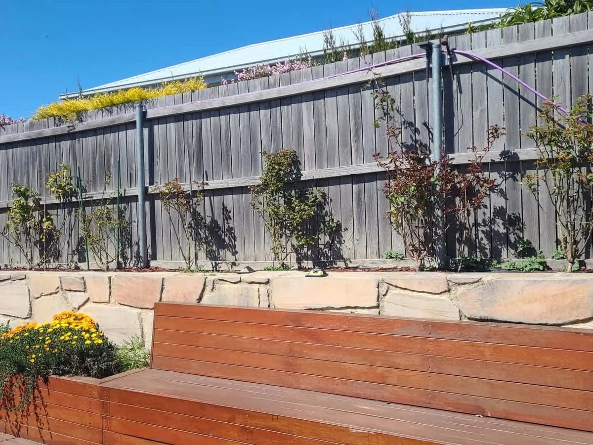 Timber fence with garden bed and sandstone wall